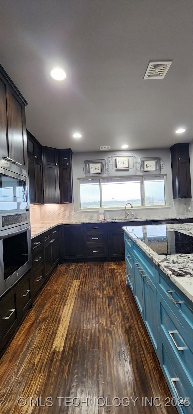 17078 S 11th W Ave, Glenpool, OK 74033 - kitchen with appliances with stainless steel finishes, dark wood-style floors, light stone counters, tasteful backsplash, and recessed lighting