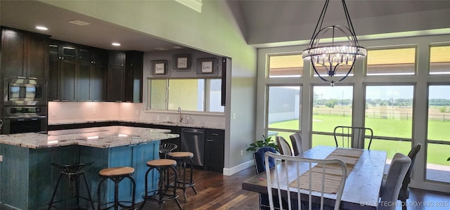 17078 S 11th W Ave, Glenpool, OK 74033 - kitchen featuring appliances with stainless steel finishes, dark wood-type flooring, decorative backsplash, a chandelier, and a breakfast bar