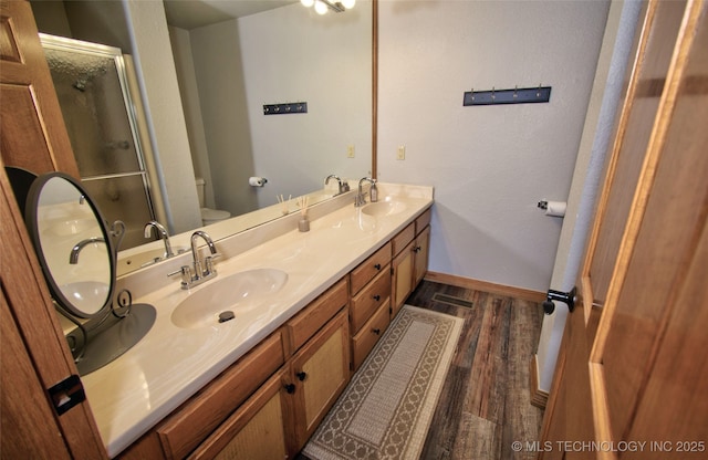 bathroom featuring a shower stall, toilet, wood finished floors, and a sink
