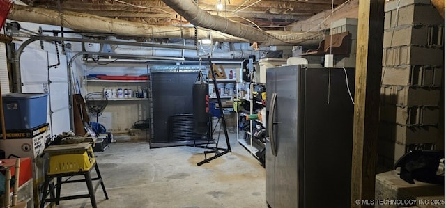 unfinished basement with freestanding refrigerator