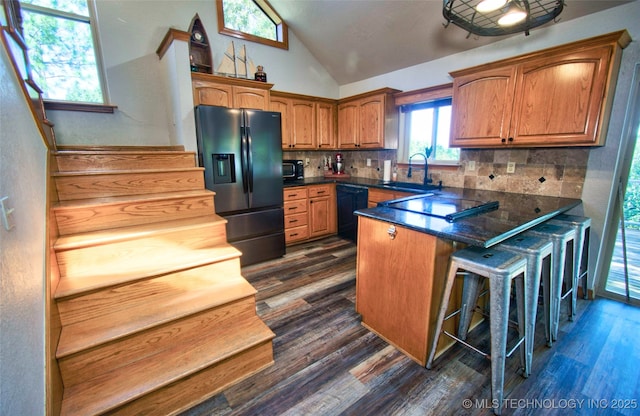 kitchen featuring a peninsula, a sink, dark wood-style floors, black appliances, and vaulted ceiling