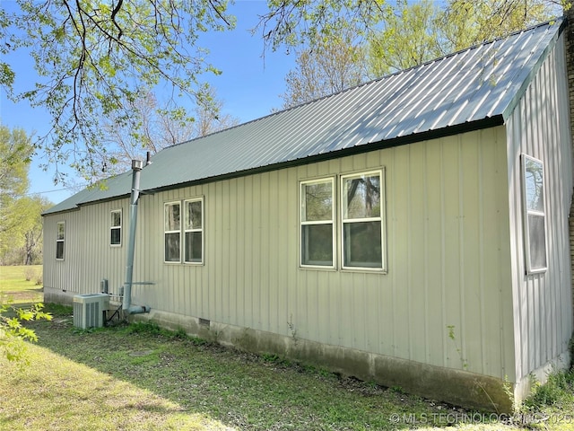 view of property exterior with crawl space, central AC unit, a yard, and metal roof