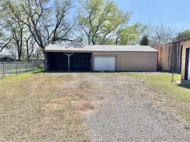 garage featuring driveway, a detached garage, and fence