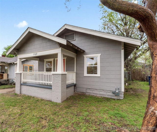 bungalow with covered porch, a front yard, and fence