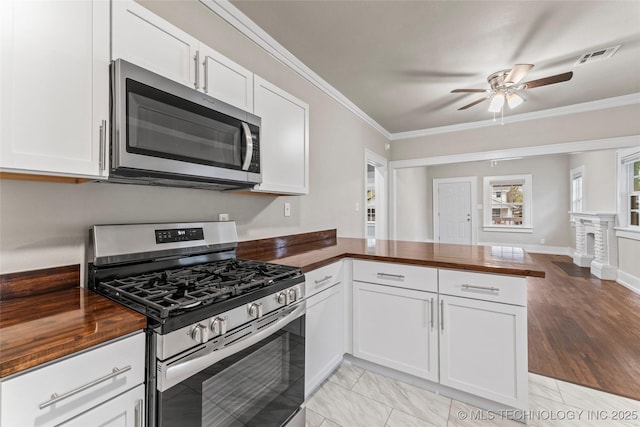 kitchen featuring butcher block countertops, ceiling fan, stainless steel appliances, and crown molding