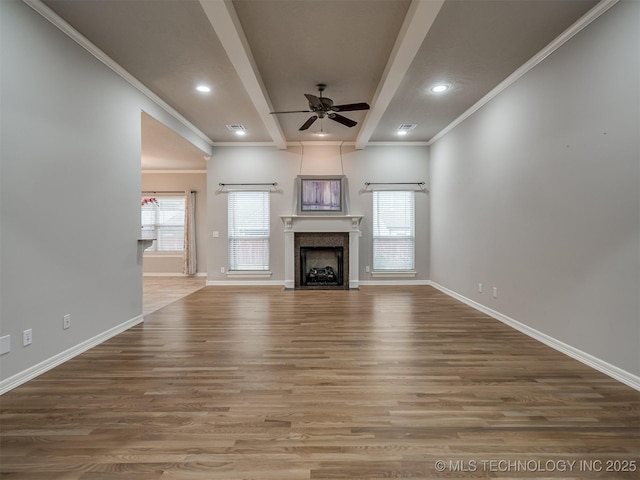 unfurnished living room with beamed ceiling, baseboards, ornamental molding, wood finished floors, and a ceiling fan