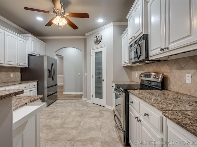 kitchen with crown molding, stainless steel appliances, white cabinets, arched walkways, and ceiling fan