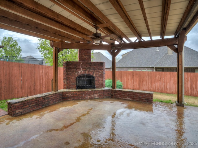 view of patio / terrace featuring an outdoor brick fireplace, a fenced backyard, and a ceiling fan
