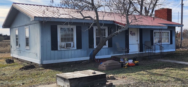 view of front of property with cooling unit, metal roof, crawl space, and a chimney
