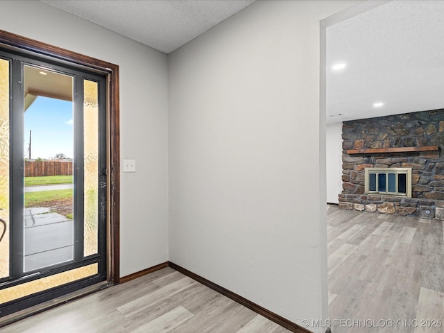 208 NE Spruce Ave, Bartlesville, OK 74006 - entrance foyer featuring light wood finished floors, baseboards, a fireplace, and a textured ceiling