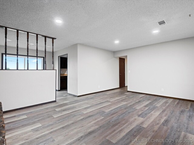 208 NE Spruce Ave, Bartlesville, OK 74006 - spare room featuring visible vents, wood finished floors, and a textured ceiling
