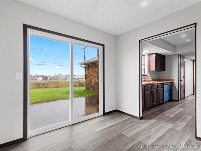 208 NE Spruce Ave, Bartlesville, OK 74006 - unfurnished dining area featuring baseboards, a textured ceiling, and light wood finished floors