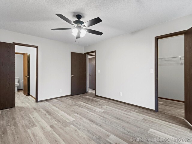 208 NE Spruce Ave, Bartlesville, OK 74006 - unfurnished bedroom with a spacious closet, a textured ceiling, and light wood-type flooring