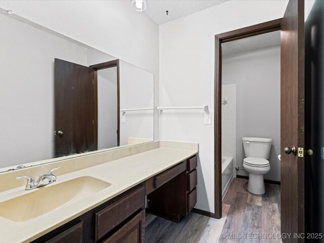 208 NE Spruce Ave, Bartlesville, OK 74006 - full bathroom with vanity, toilet, baseboards, a textured ceiling, and wood finished floors