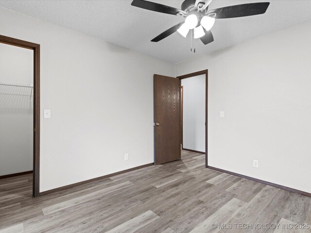 208 NE Spruce Ave, Bartlesville, OK 74006 - unfurnished bedroom featuring a closet, a textured ceiling, baseboards, ceiling fan, and light wood-style floors