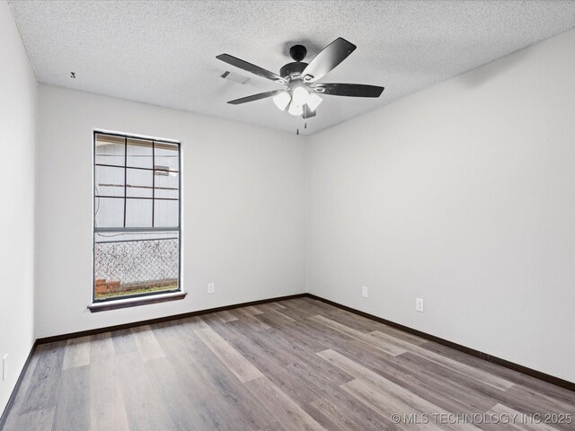 208 NE Spruce Ave, Bartlesville, OK 74006 - spare room featuring baseboards, wood finished floors, ceiling fan, and a textured ceiling