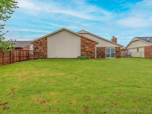 208 NE Spruce Ave, Bartlesville, OK 74006 - back of property featuring stone siding, fence, and a yard