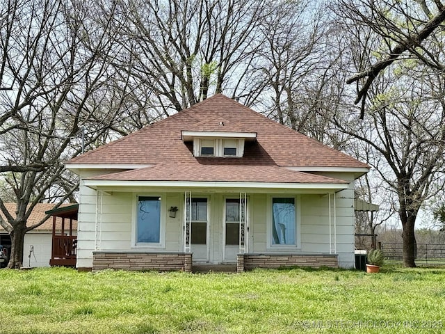 bungalow-style house with a shingled roof, fence, cooling unit, and a front yard