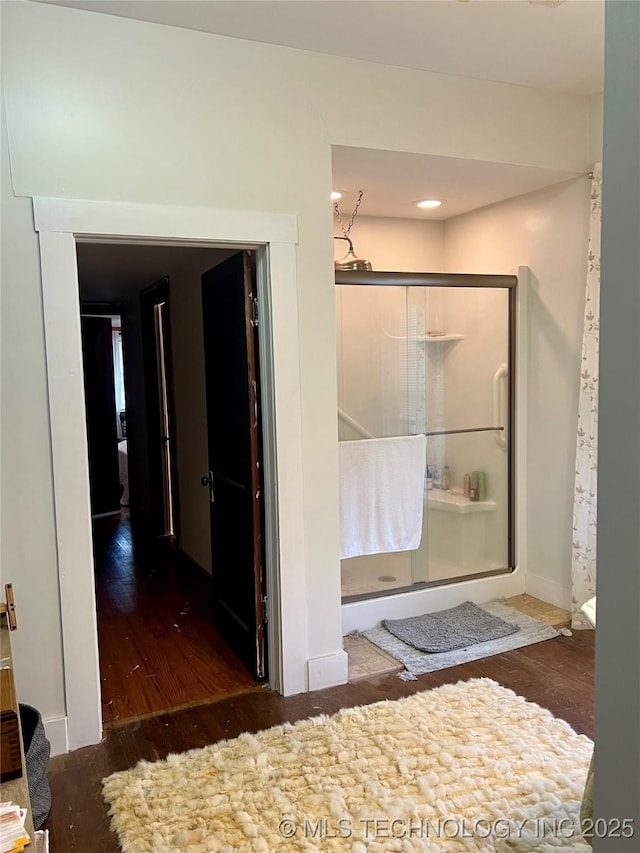 bathroom featuring a stall shower, baseboards, and wood finished floors
