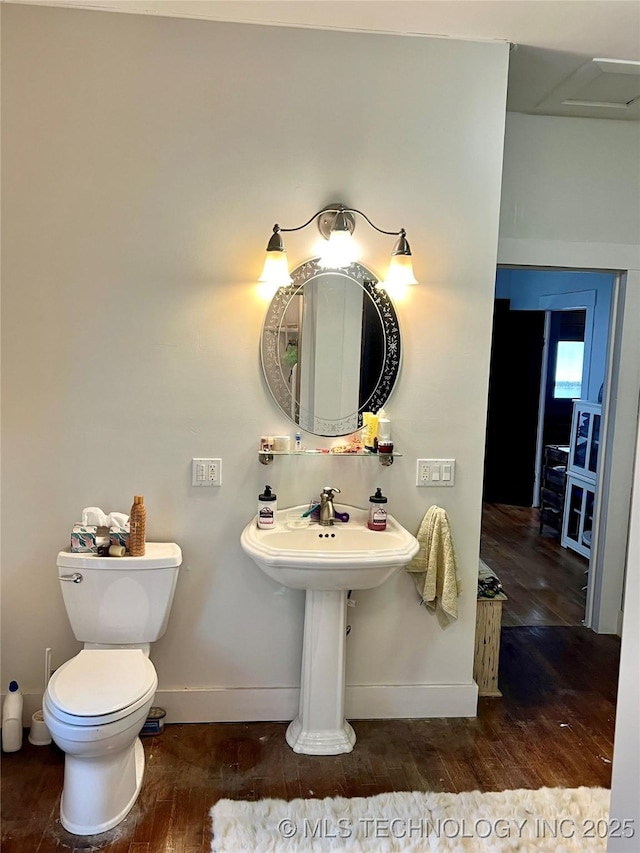 half bath with baseboards, wood finished floors, and toilet