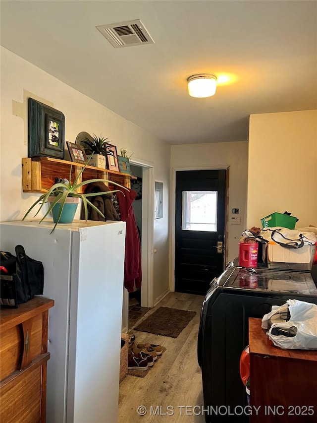interior space featuring washer and clothes dryer, visible vents, and wood finished floors