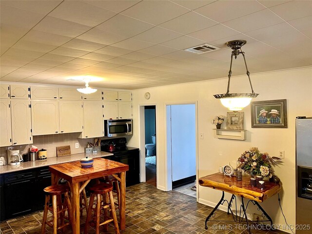 kitchen with visible vents, white cabinets, black electric range oven, and stainless steel microwave