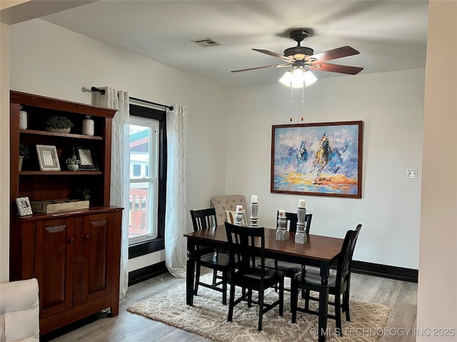 dining room featuring baseboards, light wood-style floors, ceiling fan, and visible vents