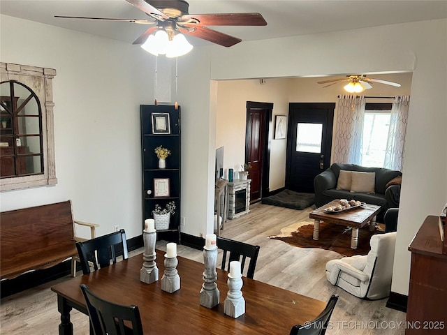 dining room with light wood finished floors, baseboards, and a ceiling fan