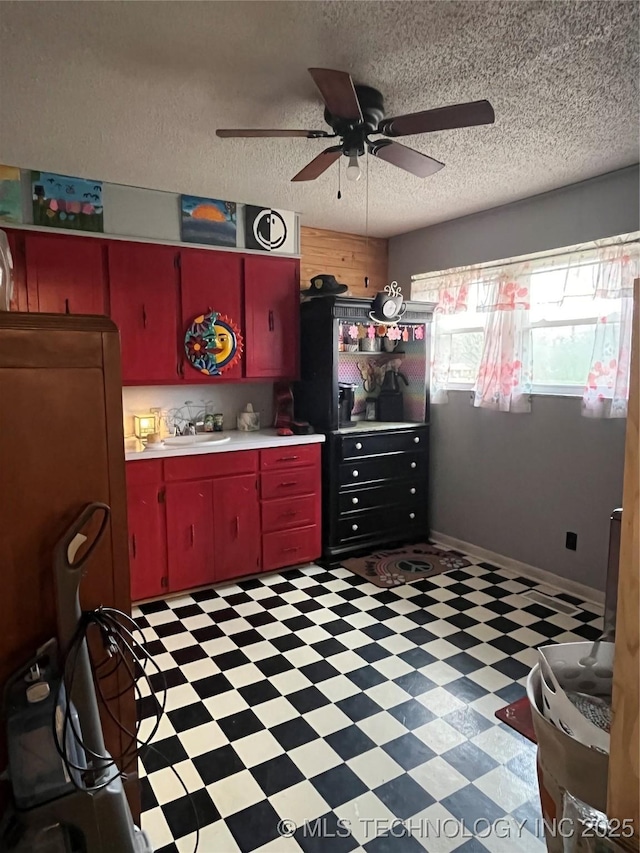 kitchen with a sink, ceiling fan, light floors, light countertops, and red cabinets