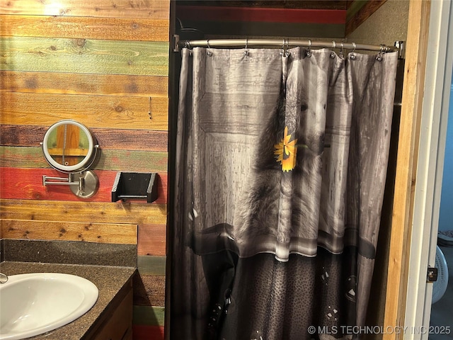 bathroom featuring wooden walls, vanity, and curtained shower