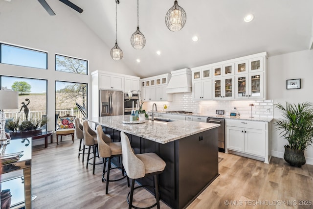 12255 Avalon Dr, Sperry, OK 74073 - kitchen featuring custom range hood, appliances with stainless steel finishes, tasteful backsplash, a center island with sink, and white cabinetry