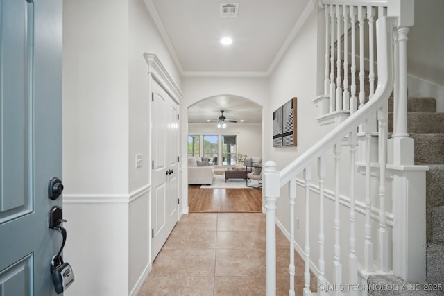 entrance foyer with ornamental molding, light tile patterned floors, a ceiling fan, stairs, and visible vents