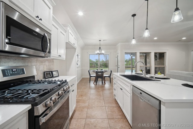 kitchen with tasteful backsplash, an inviting chandelier, light tile patterned flooring, appliances with stainless steel finishes, and a sink