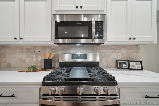 kitchen featuring stainless steel appliances, white cabinetry, and backsplash