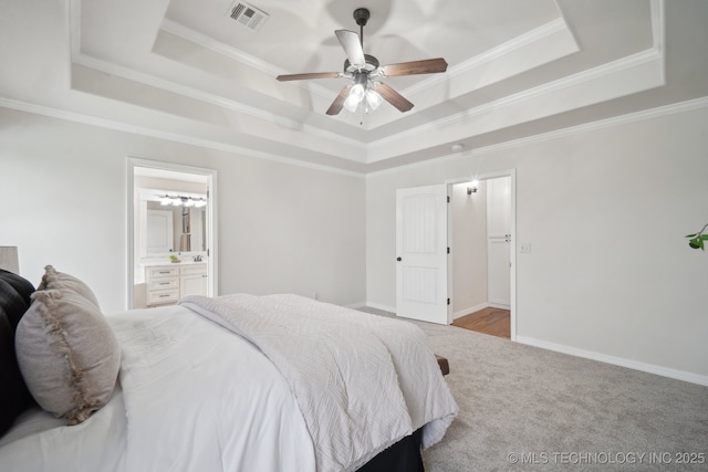 carpeted bedroom featuring a raised ceiling, crown molding, ensuite bathroom, and visible vents
