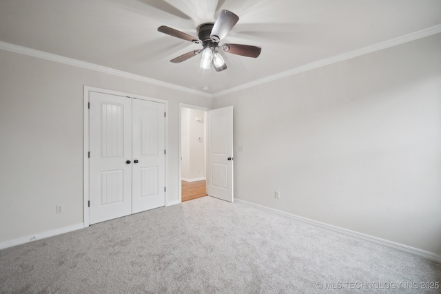 unfurnished bedroom with crown molding, carpet floors, baseboards, and a closet