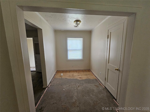 corridor with a textured ceiling, ornamental molding, and baseboards