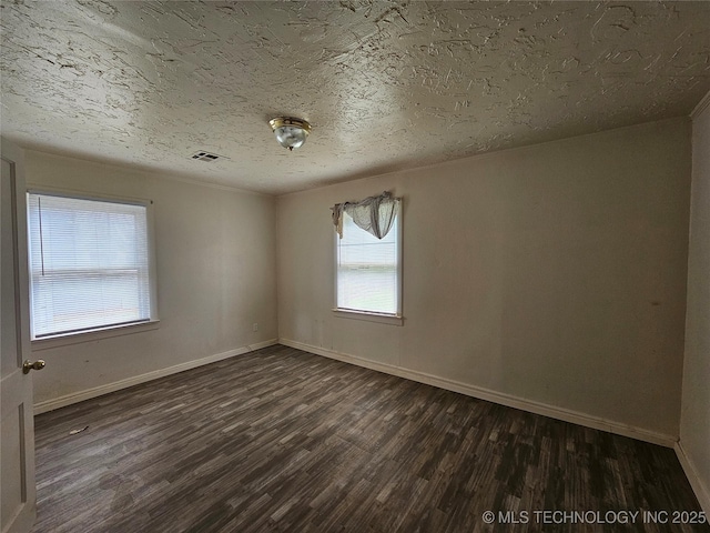 unfurnished room featuring baseboards, visible vents, dark wood-type flooring, and a textured ceiling