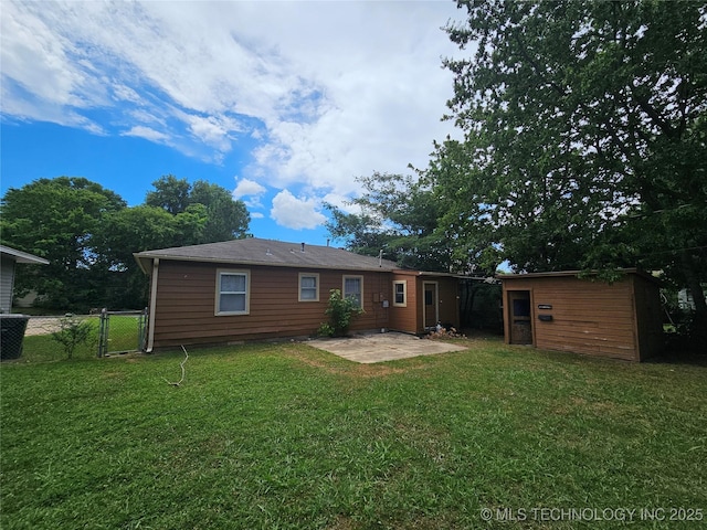rear view of house featuring an outdoor structure, a shed, fence, a patio area, and a lawn