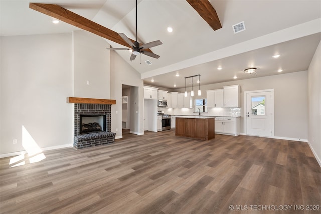 unfurnished living room with wood finished floors, ceiling fan, beam ceiling, and visible vents