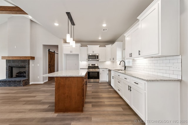 kitchen featuring appliances with stainless steel finishes, a sink, lofted ceiling, and a barn door