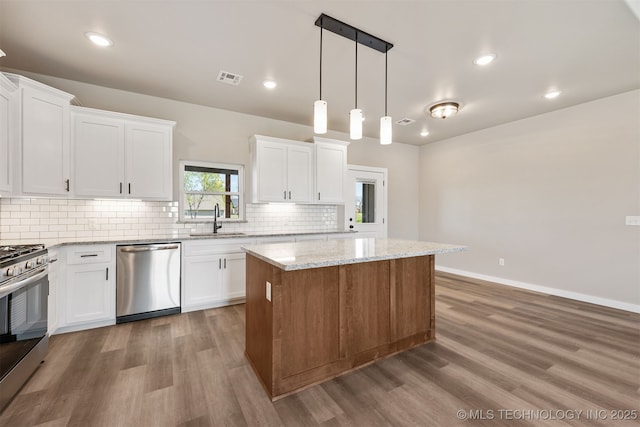 kitchen featuring visible vents, a sink, stainless steel appliances, decorative backsplash, and a kitchen island