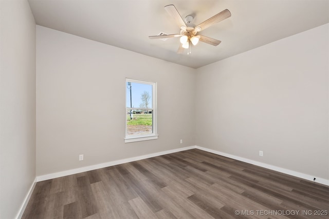 spare room with dark wood-style flooring, ceiling fan, and baseboards