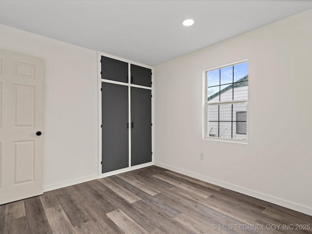 unfurnished bedroom with recessed lighting, a closet, baseboards, and wood finished floors
