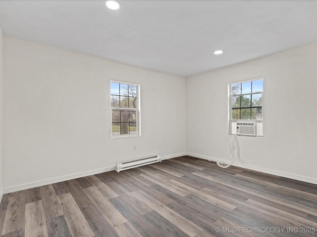 spare room featuring plenty of natural light, baseboards, baseboard heating, and wood finished floors
