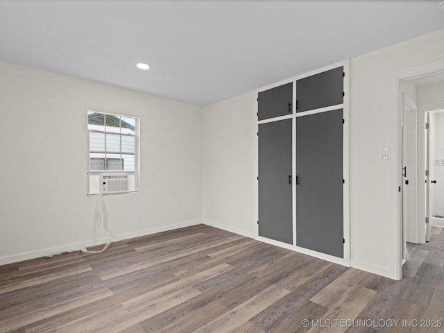unfurnished bedroom featuring baseboards, wood finished floors, recessed lighting, and cooling unit