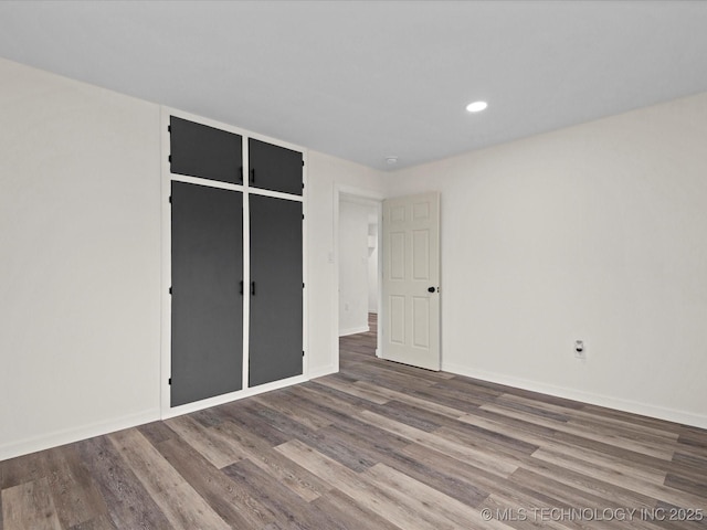 unfurnished bedroom with baseboards, a closet, wood finished floors, and recessed lighting