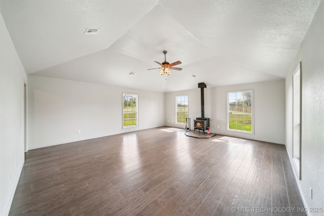 9839 N Lewis Ave, Sperry, OK 74073 - spare room with ceiling fan, visible vents, vaulted ceiling, a wood stove, and wood finished floors