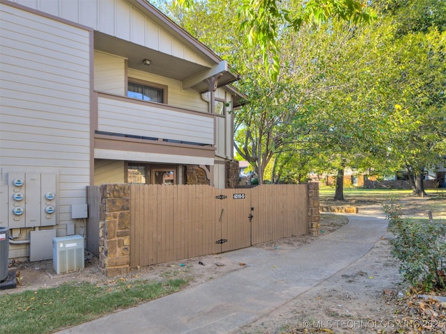 6510 S Memorial Dr Unit G, Tulsa, OK 74133 - view of side of home featuring central air condition unit, fence, board and batten siding, a balcony, and a gate