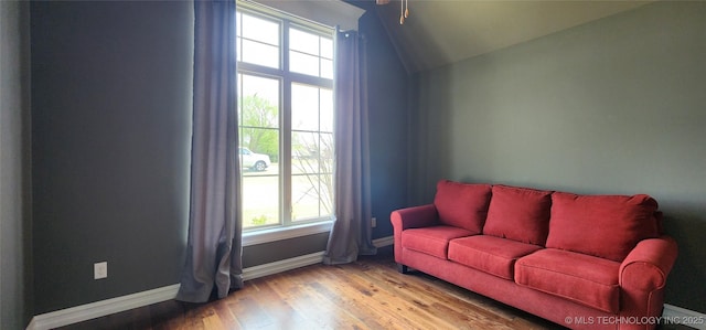 living area with vaulted ceiling, wood finished floors, and baseboards
